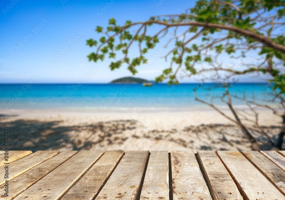 Fototapeta premium Wooden table top on the beach or sea.Party on the beach sunshine time concept.For montage product display or design key visual layout.View of copy space.