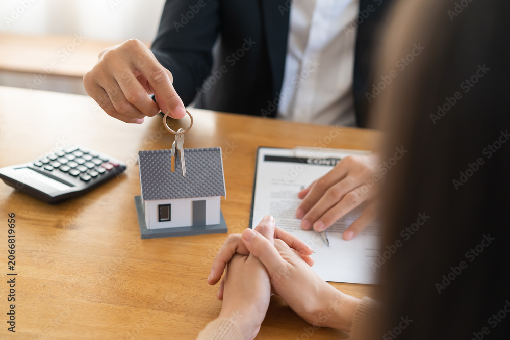 Naklejka premium Close up agent giving a key to new owner or tenant, client after signed signature contract rental purchase, buyer apartment, home with landlord, realtor. Banker agreement mortgage loan. Property lease