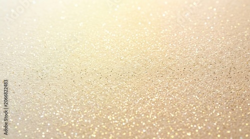 A blurred background of gold glitter sparkles on a beige surface.