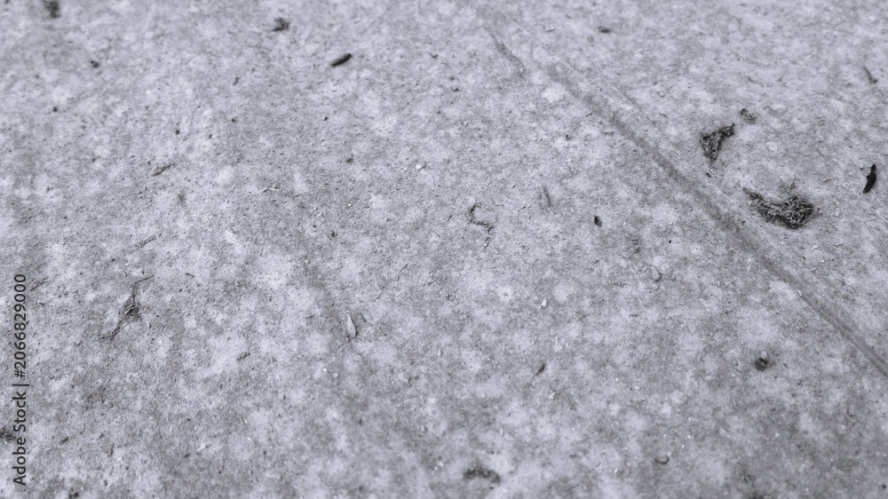 Fototapeta premium Monochrome close-up of pale dusty floor surface with fine debris, subtle track marks, and minimal rough texture.