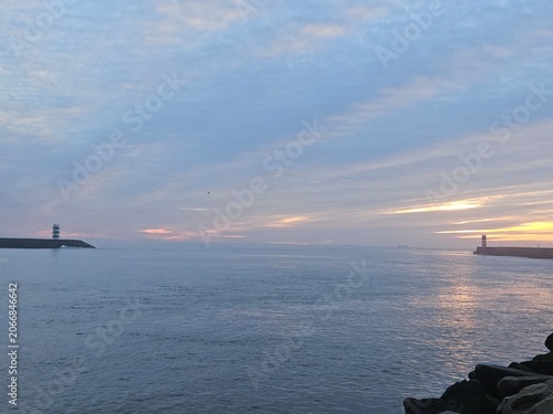 Beautiful scenic ocean sunset over the Douro river mouth with lighthouses in Porto