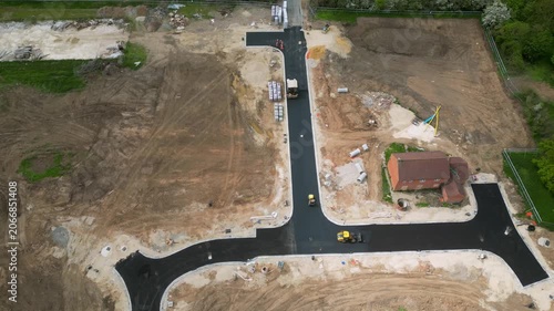 Machineries work on building a new road at the Bellway site in Boroughbridge, UK. Workers and equipment move dirt and asphalt to create the road