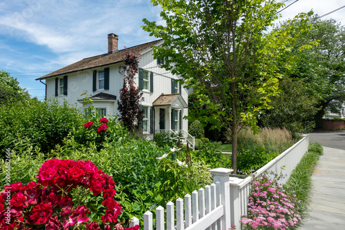 Bild auf Leinwand A charming white house with green shutters in a Southport (Fairfield), Connecticut neighborhood with a white picket fence and flowers