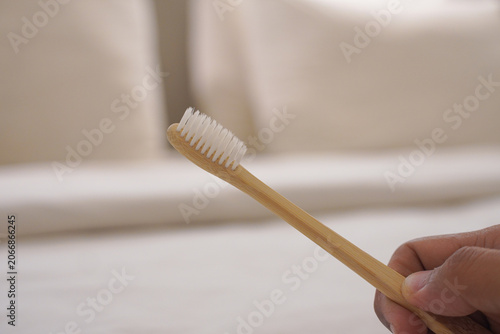 Ideal for ecoconscious dental products, this wooden bamboo toothbrush features white nylon bristles, soft handle, and organic material with human hand grip. Great for sustainability blogs or hygiene p