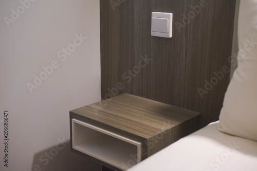 Perfect addition to bedroom visual content. Wooden nightstand, white bedding, and home decor. Ideal for furniture brands and interior designers.