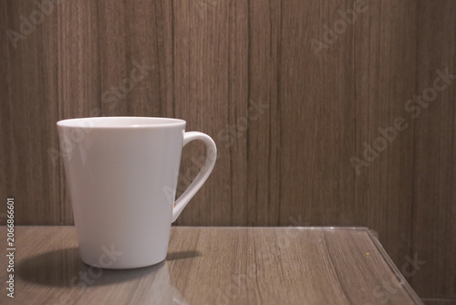 Single white ceramic coffee mug on a wooden background depicting a smooth surface on a clean kitchen table. Suitable for kitchen themed designs.