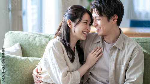 リビングのソファで寄り添いながら微笑むカップル