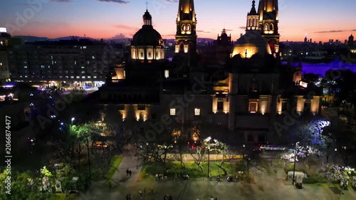 Drone elevating video of Tapatia Plaza, Guadalajara at night. Illuminated fountain and vibrant city life at dusk.