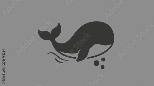 A black whale swims underwater in the ocean with bubbles rising.