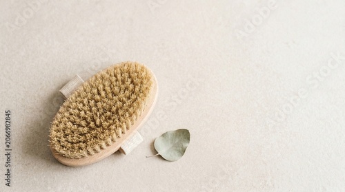 Natural body brush and eucalyptus leaf on beige surface  