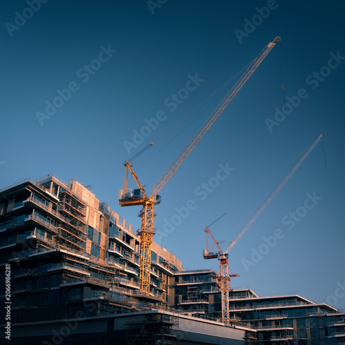 Construction site of modern residential buildings in scaffolding with cranes at day, Abu Dhabi