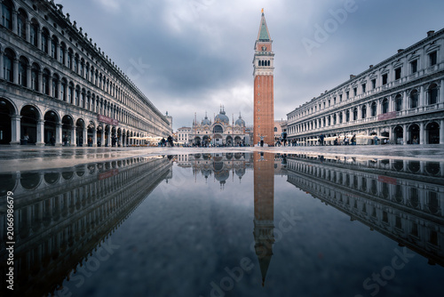 Piazza San Marco iconic view with basilica, Campanile and buildings reflected in water, Venice, Italy
