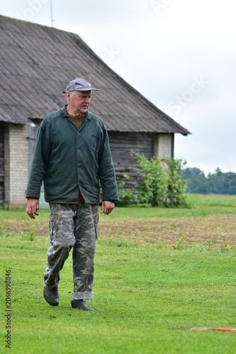 Obraz na plátně Elderly farmer walking across a rural homestead near a traditional wooden barn
