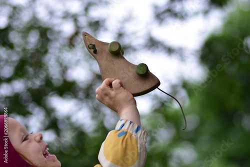 Foto Happy toddler holding a vintage wooden rat toy outdoors