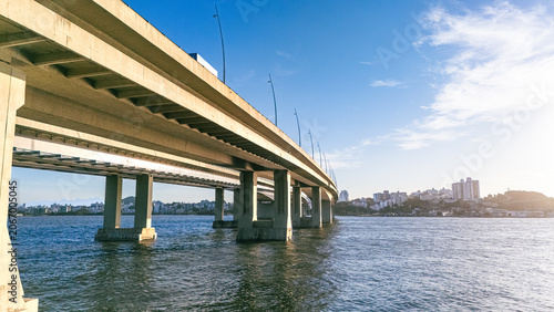 Low Angle View of Concrete Highway Bridge Over Ocean Bay with City Skyline at Sunset in Florianopolis Brazil