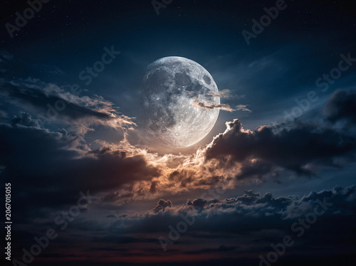 A massive luminous full moon peeks through layered shadowed cumulus clouds dotted with faint tiny stars; warm golden rim glow illuminates cloud edges against deep dark indigo night sky.