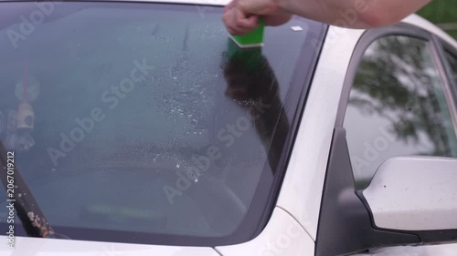 A man washes car windows with detergent before applying anti-rain