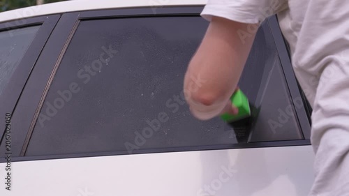 A man washes car windows with detergent before applying anti-rain