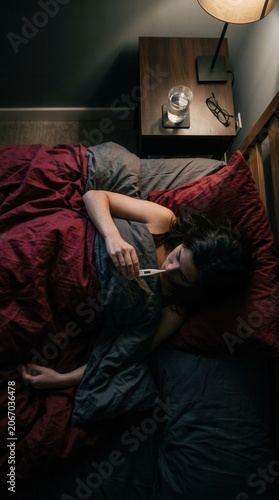 Young Woman Feeling Unwell Takes Temperature in Bed While Sick