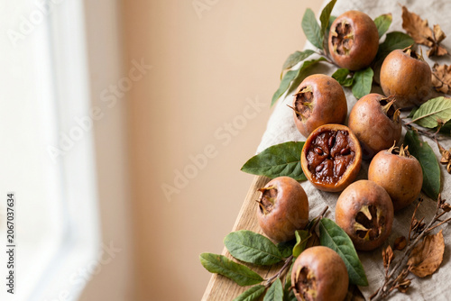 Organic ripe medlar fruits with green leaves on a rustic wooden table