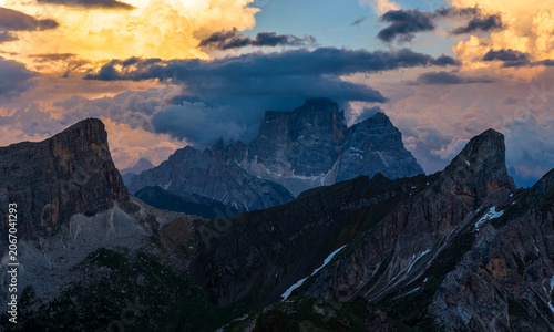 Obraz na płótnie Dramatic storm clouds engulf rugged Dolomite mountain peaks at sunset in northern Italy