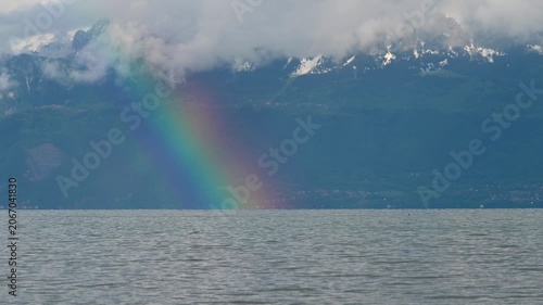 Real Time Rainbow over Lake Geneva and mountain in cloudy day. Preverenges, Vaud, Switzerland.
