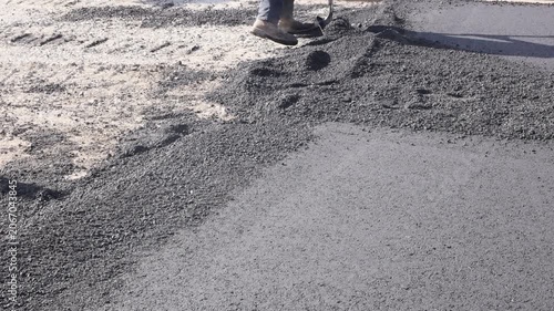 Workers are applying asphalt to road surface at construction site during road repair work