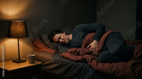 Woman Suffering In Bed At Night With Expression Of Pain And Exhaustion