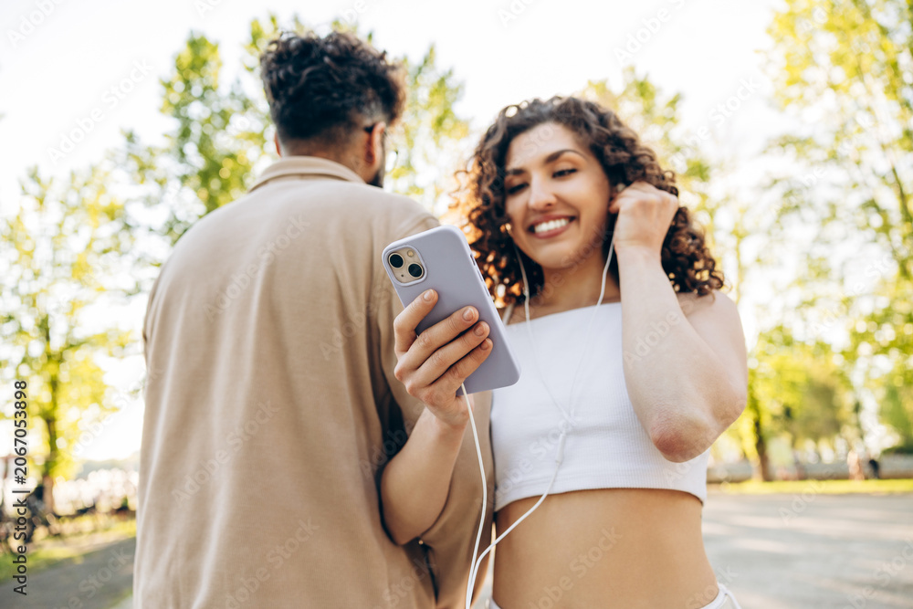 Obraz premium Young couple enjoying music and walking in park