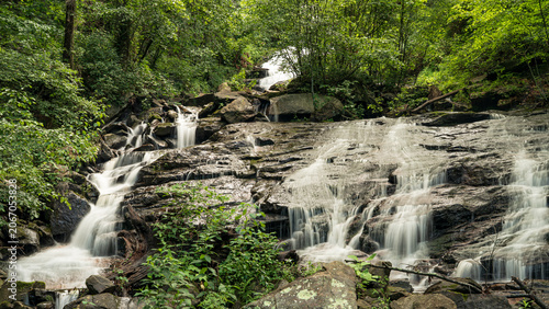 Multi-tiered cascade waterfall flowing through dense green forest at Amicalola Falls State Park, North Georgia mountains, USA.