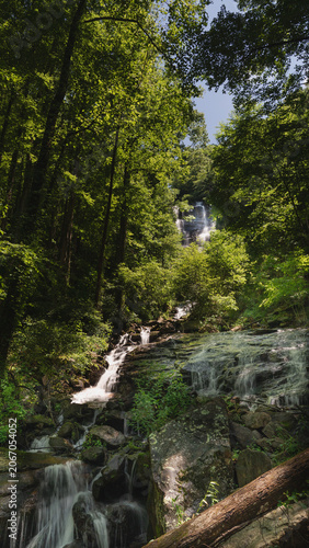 Multi-tiered cascade waterfall flowing through dense green forest at Amicalola Falls State Park, North Georgia mountains, USA.