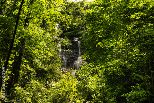 Multi-tiered cascade waterfall flowing through dense green forest at Amicalola Falls State Park, North Georgia mountains, USA.