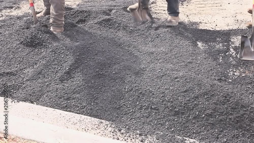 Workers are using shovels to move gravel at construction site