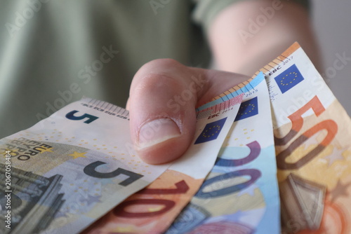 Man holding euro bills and handing it over, giving bank notes to somebody else, financial transaction
