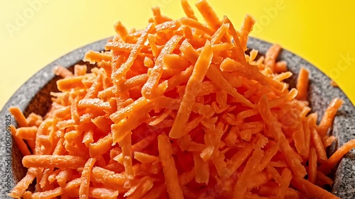 Pouring shredded carrots into a rustic stone bowl.