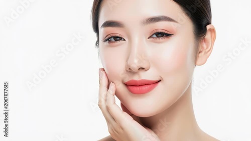 Flawless Beauty: A young woman with radiant skin and a gentle smile poses with her hand delicately touching her cheek, embodying natural elegance and self-care.
