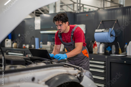 Auto mechanic performing car diagnostics using a laptop