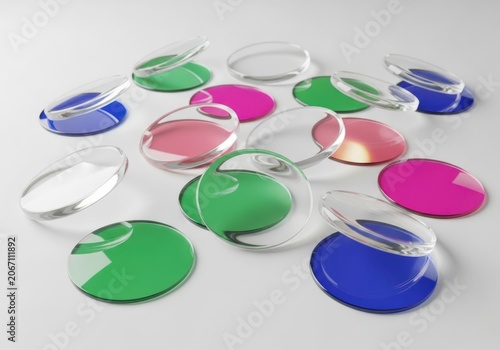 Scattered collection of colorful, translucent, circular glass lenses or filters on a plain white surface