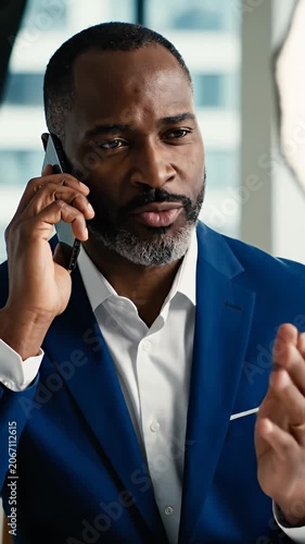 Smiling Black businessman talking on a smartphone in office.