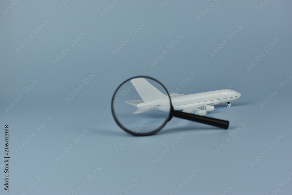 Fototapeta premium White model airplane sits under magnifying glass