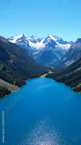 Wide aerial view of blue lake in mountain valley.