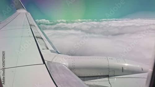 Beautiful view of airplane wing above thick clouds seen through passenger window.