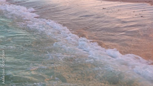 Close-up view of breaking Atlantic Ocean wave on background of sandy beach at sunset. Miami Beach. USA.