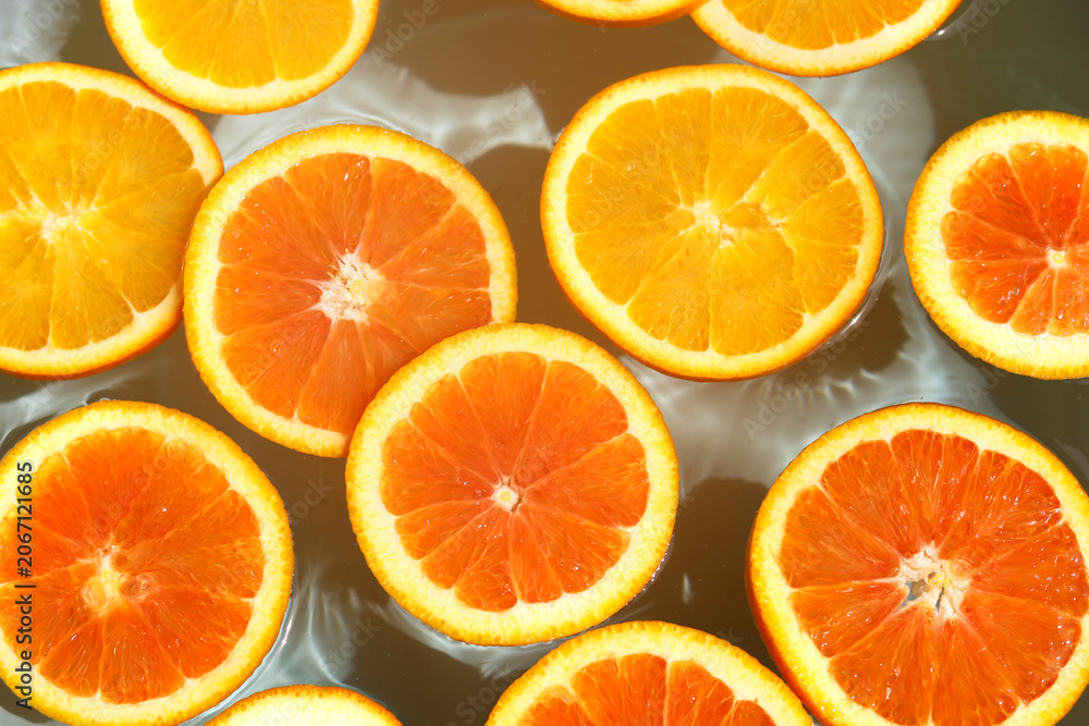 Obraz premium Juicy orange slices floating in clean, clear rippling water.