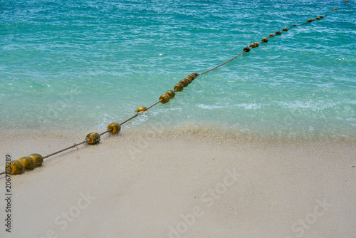Floating Buoy Rope Line in Turquoise Sea with Gentle Waves on Sandy Beach