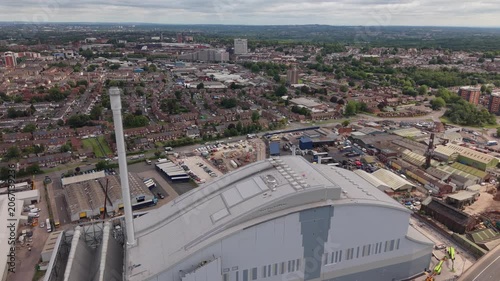 Top down aerial drone view of commercial business premises, warehouse units, company vehicles and industrial yard within a business park in the West Midlands, England. 