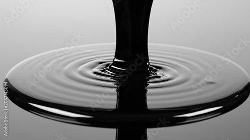 Thick viscous black liquid pouring and spreading, creating ripples, abstract dark fluid flow