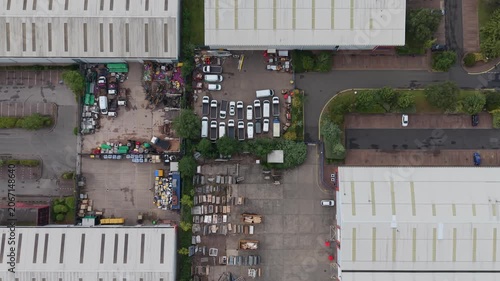 Top down aerial drone view of commercial business premises, warehouse units, company vehicles and industrial yard within a business park in the West Midlands, England. 