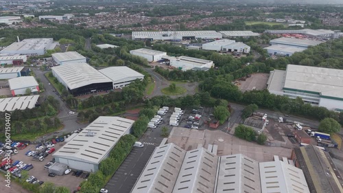 Aerial drone flyover above commercial warehouses, logistics facilities and industrial business units in the West Midlands, England. Modern distribution and commercial property area with parking, servi
