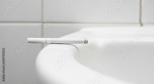 An Unlit Cigarette Resting on the Edge of a White Bathtub